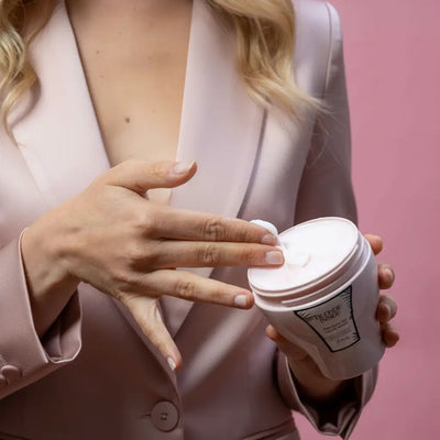 Un barattolo cilindrico bianco con coperchio coordinato ed etichetta nera, contenente un prodotto cremoso.