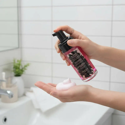 Bottiglia di shampoo rosa schiumante con etichetta floreale nera e pompa, marchiata come wella blonde inside.