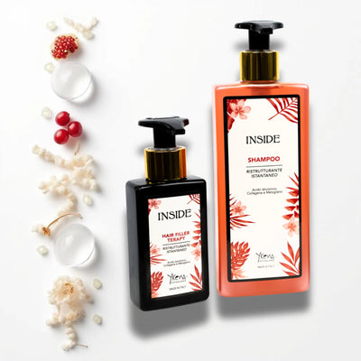 Due bottiglie rettangolari di prodotti per la cura dei capelli interni, una nera e una corallo-arancio, entrambe con pompe dorate e etichette floreali con ’hair filler therapy’ e ’shampoo’ scritto in inglese.