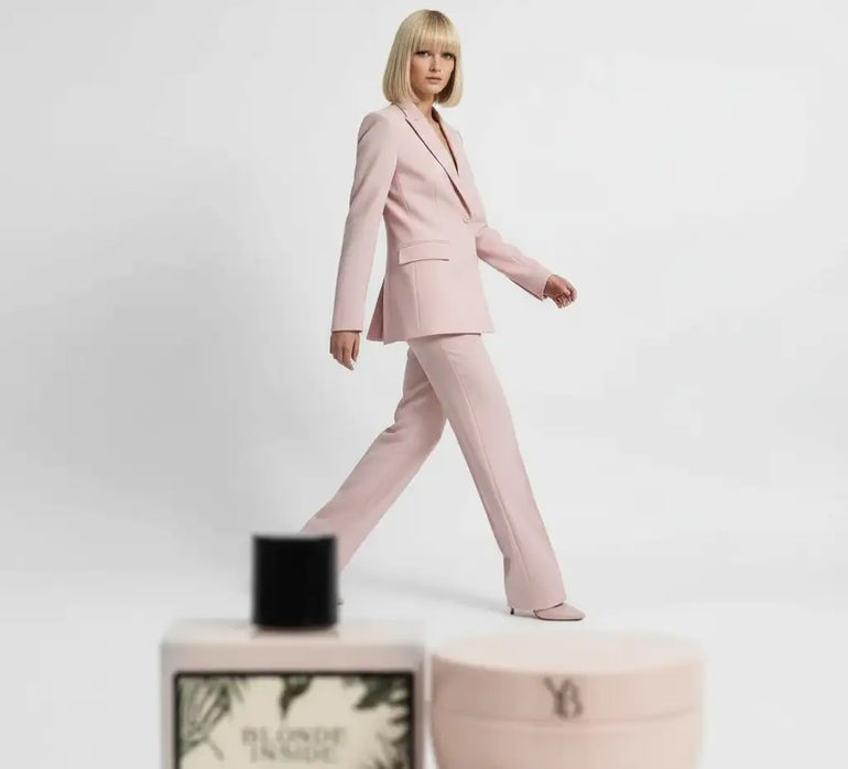 Una donna in un elegante completo sartoriale rosa chiaro con pantaloni a gamba dritta e blazer a un bottone.