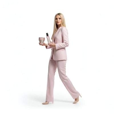 La donna indossa un elegante completo sartoriale rosa chiaro con pantaloni e blazer coordinati.