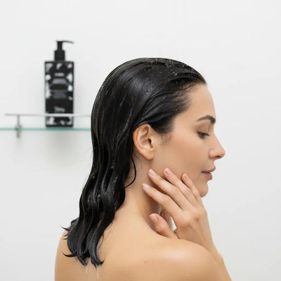 Una elegante bottiglia a pompa nera con finitura opaca è posata sullo scaffale di vetro.