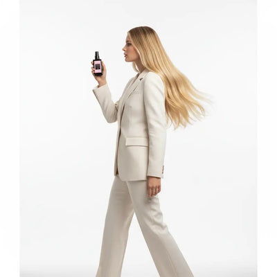 Una elegante bottiglia spray nera con etichetta rosa, tenuta in mano alla donna.