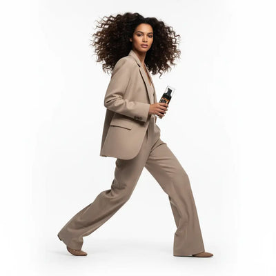 Una elegante bottiglia spray trasparente con pompa nera ed etichetta con accenti dorati.