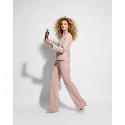 Una elegante bottiglia spray trasparente con pompa nera ed etichetta rosa vivace.