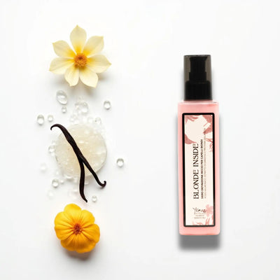 Flacone rettangolare rosa di prodotto per capelli biondo con ugello spray nero ed etichetta floreale.