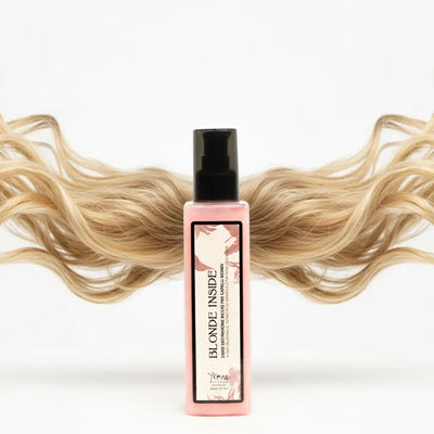 Flacone rosa di spray per trattamento capelli con biondo all'interno, pompa nera ed etichetta floreale.